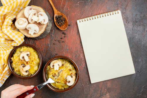 top-view-tasty-julienne-bowls-fork-female-hand-notepad-wooden-spoon-dark-red-table.jpg